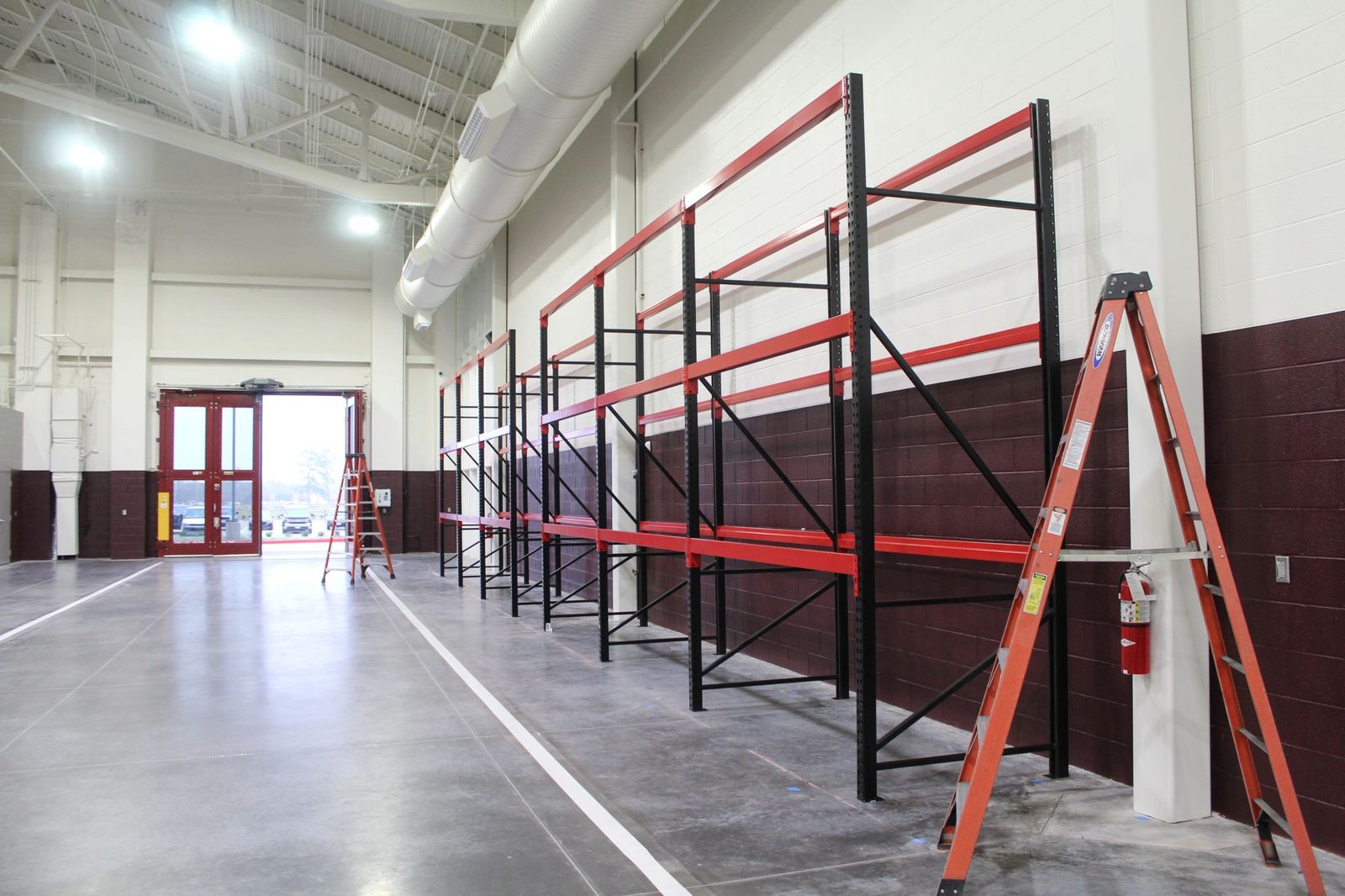 Custom black upright and red beam pallet racking along a finished interior wall
